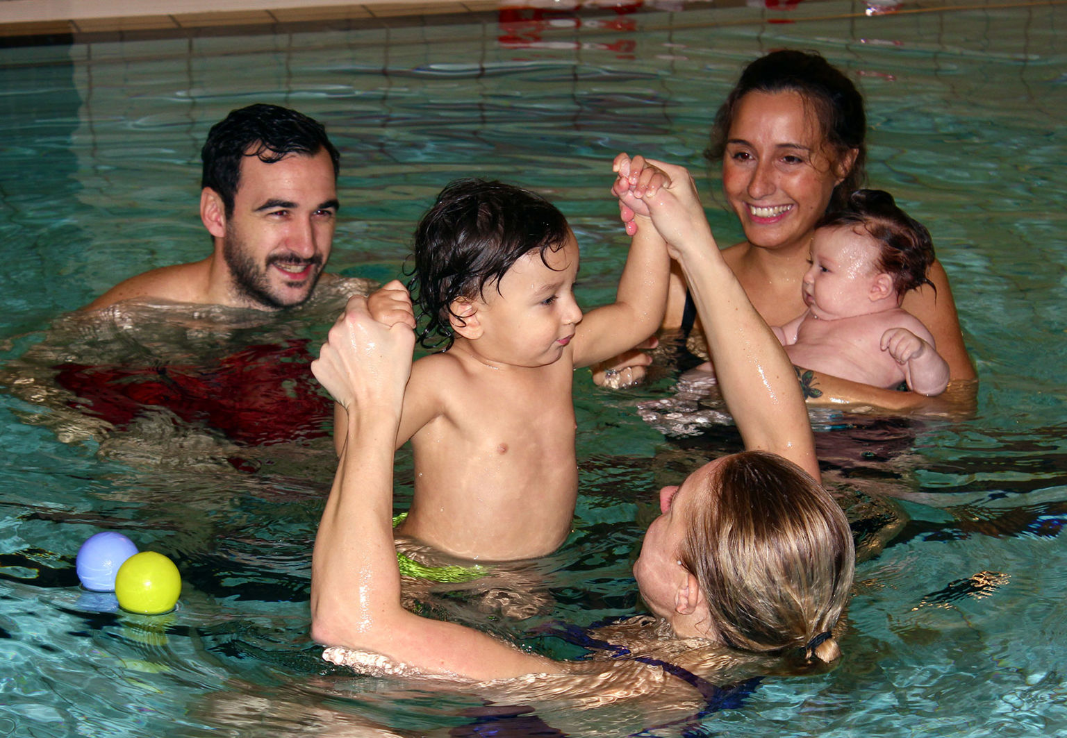 Familj med bebis i en pool inomhus