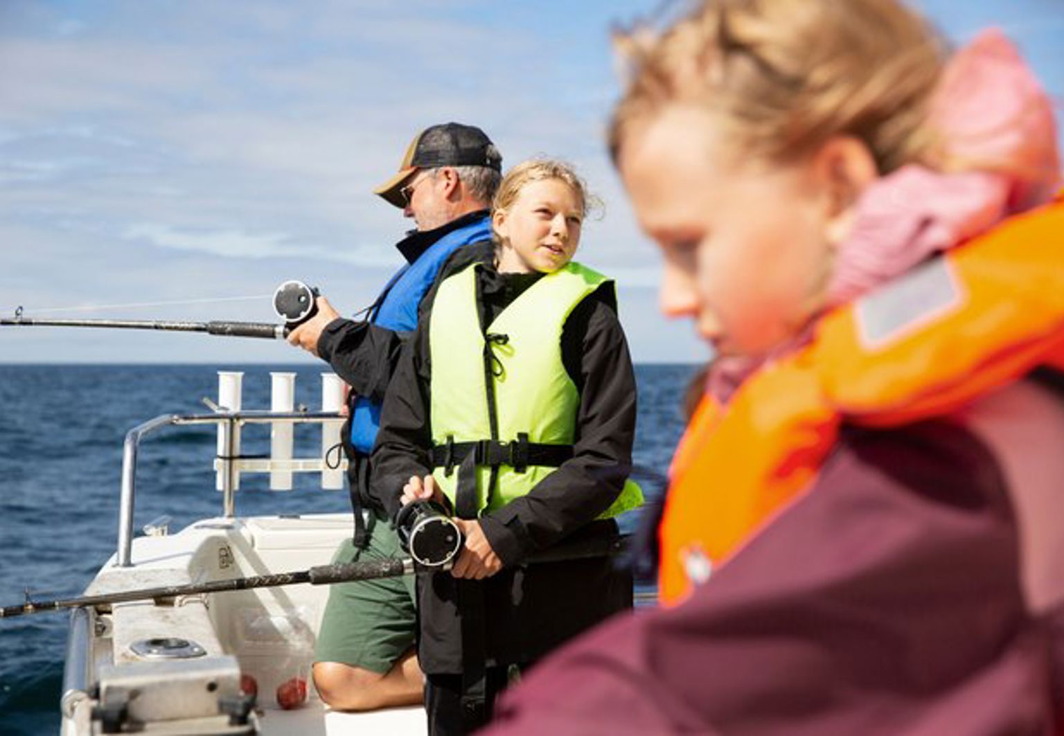 Barn och en vuxen fiskar från en båt