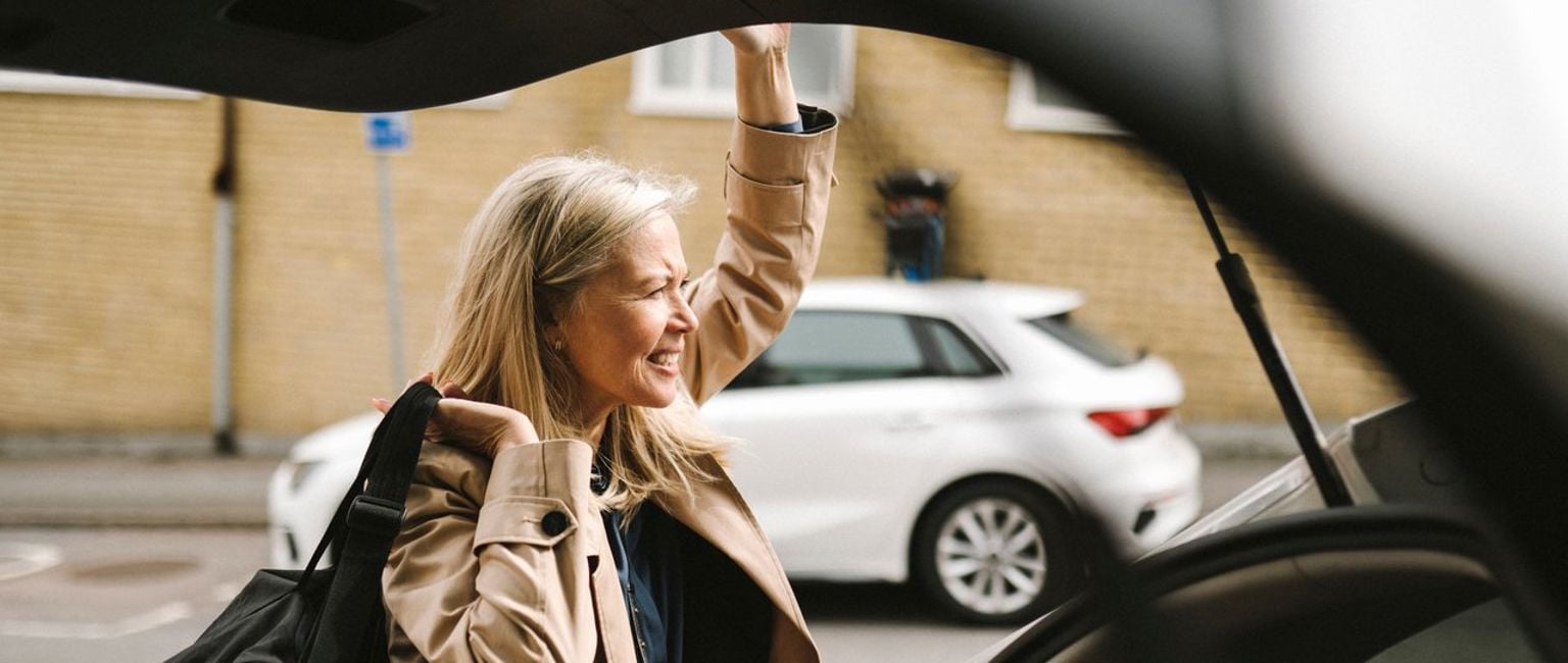 Kvinna har parkerat bilen och hämtar väska från bagageutrymmet