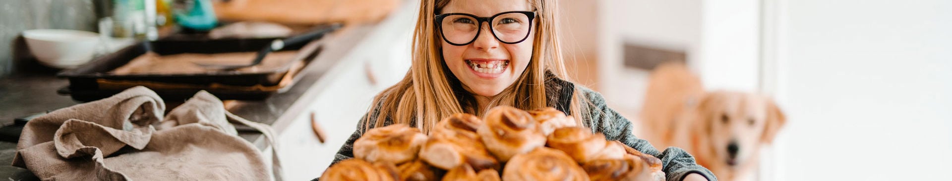 glad flicka håller en plåt med kanelbullar