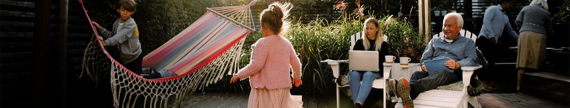 Familj sitter i trädgården under sommaren