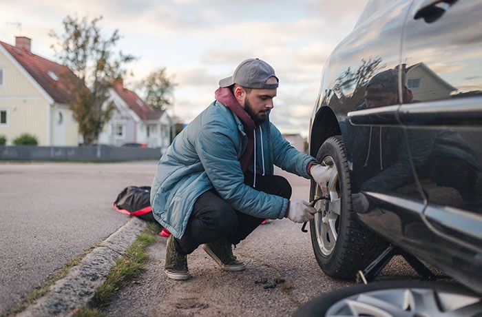 person byter däck på bil