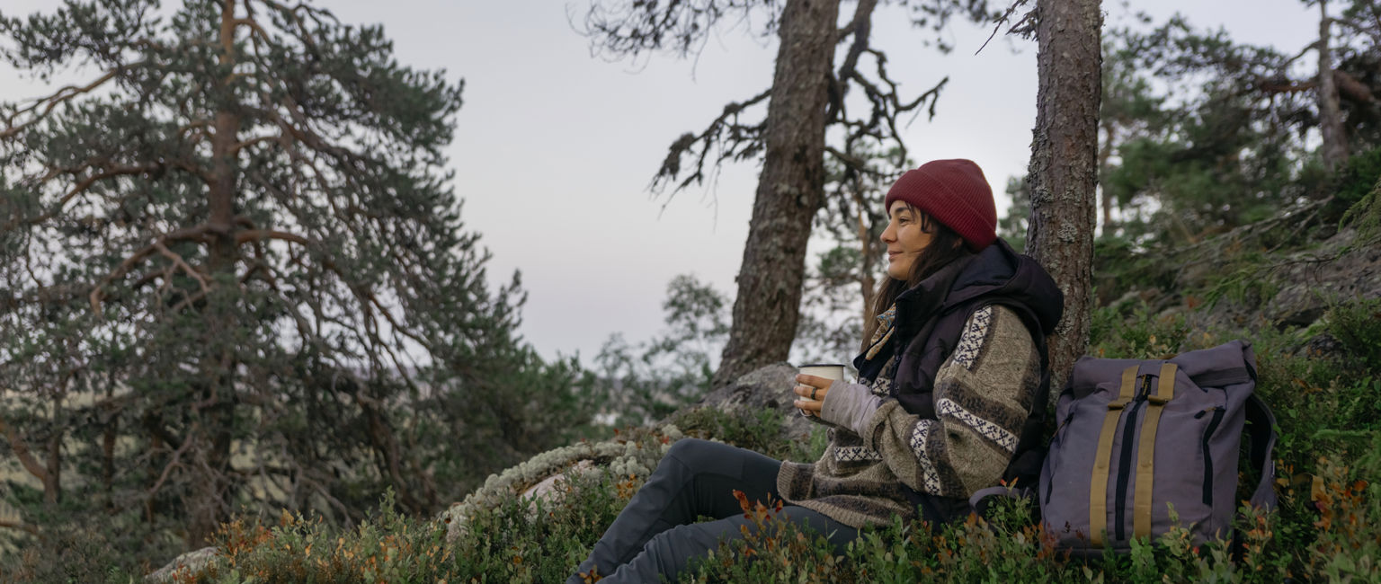 kvinna tar en fikapaus i skogen