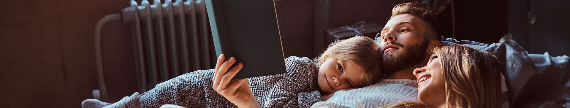 familj ligger i säng och tittar på ipad