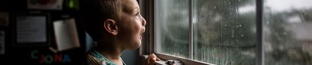 pojke tittar ut genom fönstret vid storm