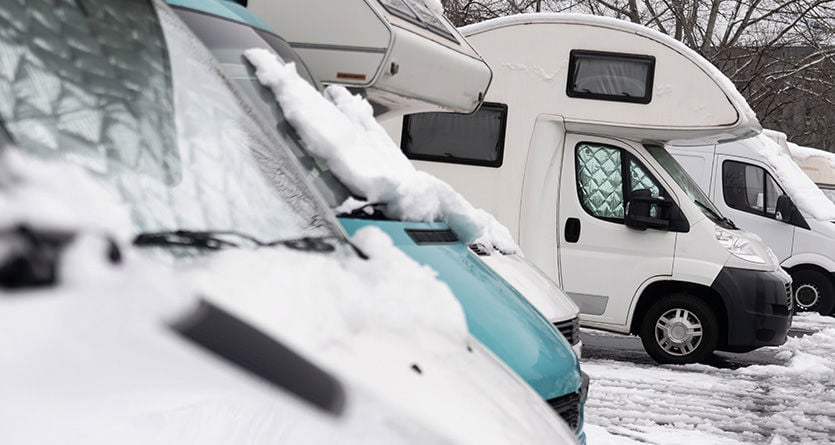 Flera husbilar som står utomhus och är snötäckta