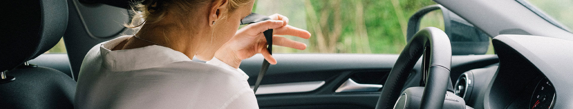 kvinna sätter på sig säkerhetsbälte i bil