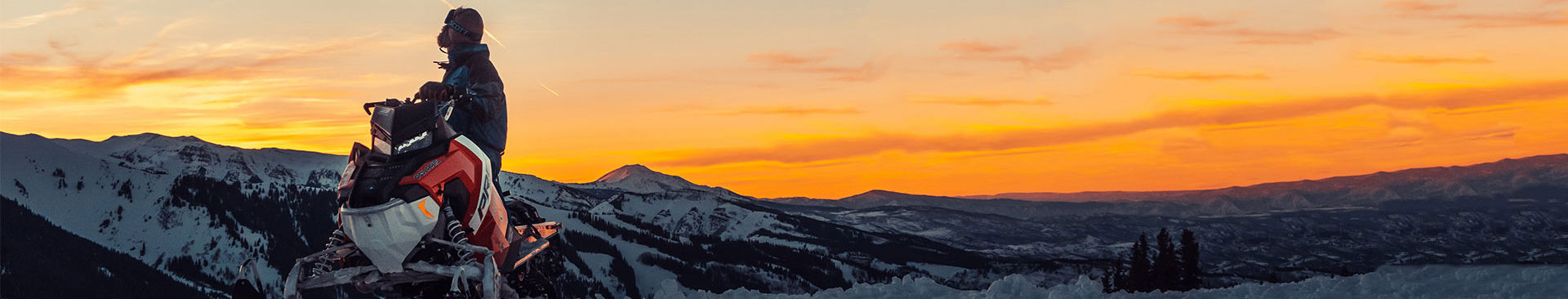 man vid sin snöskoter i solnedgång